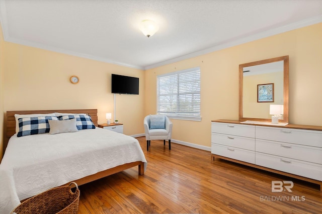 bedroom featuring ornamental molding, light wood-style floors, and baseboards