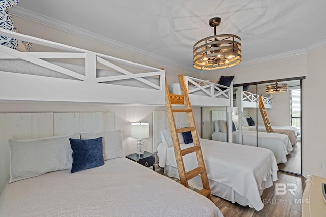bedroom with an inviting chandelier, ornamental molding, and wood finished floors