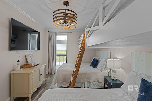 bedroom with an inviting chandelier, ornamental molding, wood finished floors, and baseboards