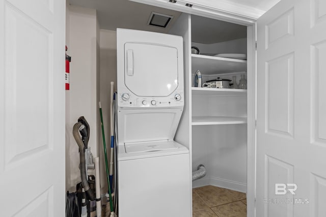 washroom with stacked washer and clothes dryer, tile patterned flooring, and laundry area