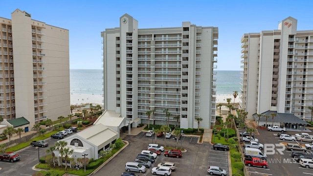 view of property with a view of the beach, a water view, and uncovered parking