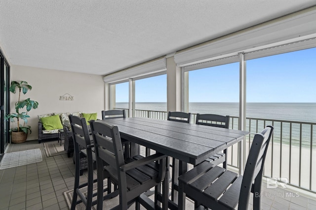 dining space featuring plenty of natural light, tile patterned floors, a textured ceiling, and a water view