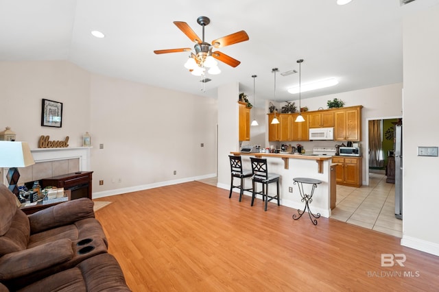 living room featuring ceiling fan, light hardwood / wood-style floors, and lofted ceiling