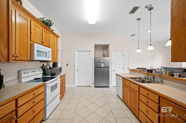 kitchen with appliances with stainless steel finishes, light tile patterned floors, hanging light fixtures, and sink