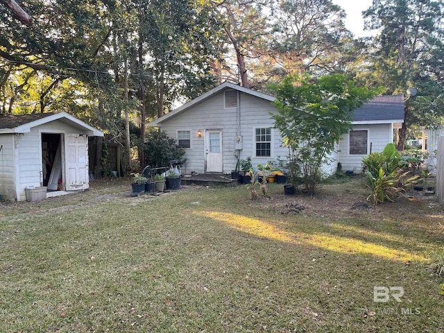 back of house with a yard and a shed