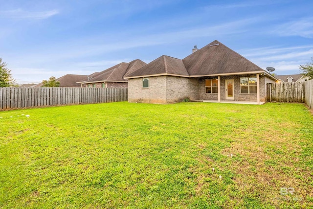1077 Crown Walk Dr, Foley, AL 36535 - rear view of property featuring a chimney, a fenced backyard, brick siding, roof with shingles, and a yard