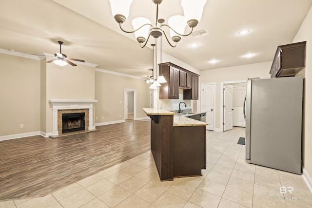 1077 Crown Walk Dr, Foley, AL 36535 - kitchen with crown molding, dark brown cabinetry, a sink, freestanding refrigerator, and ceiling fan with notable chandelier