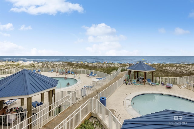 view of pool featuring a gazebo, a water view, and a beach view