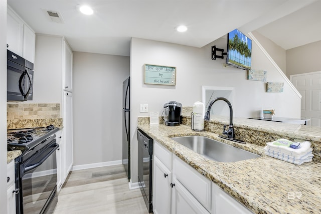 kitchen with backsplash, light stone counters, sink, black appliances, and white cabinetry