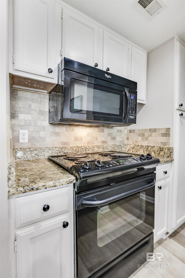 kitchen featuring light stone countertops, tasteful backsplash, white cabinetry, and black appliances