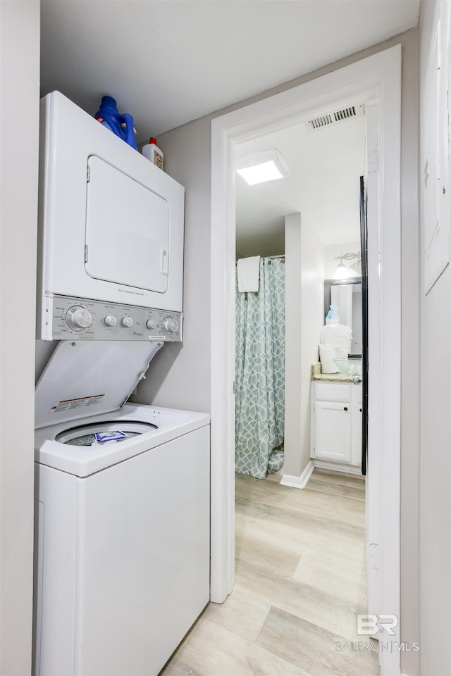 laundry area featuring light wood-type flooring and stacked washer and dryer