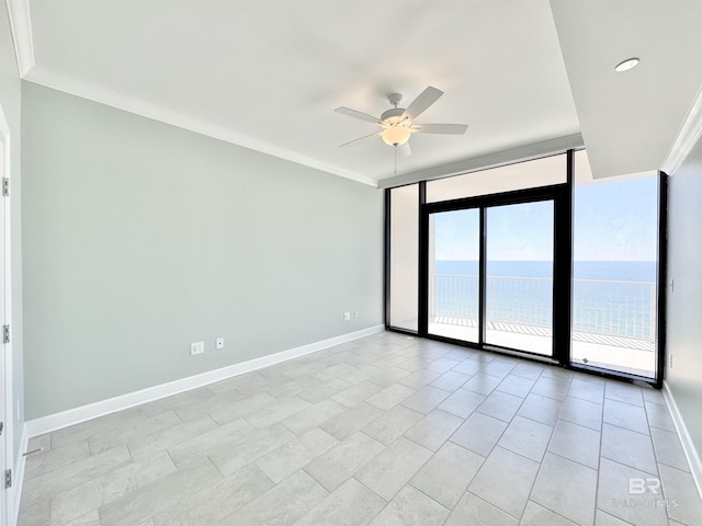 empty room with ceiling fan, a wall of windows, baseboards, and ornamental molding