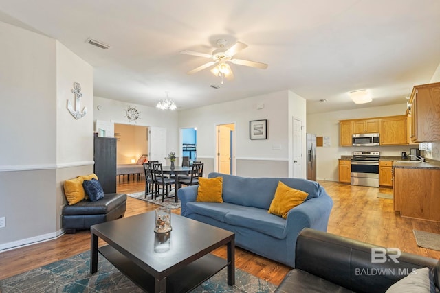 living room featuring light hardwood / wood-style floors, sink, and ceiling fan with notable chandelier