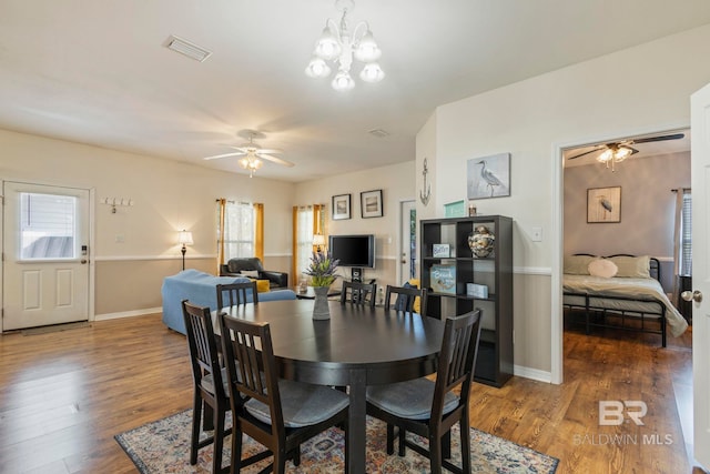 dining room with ceiling fan with notable chandelier and dark hardwood / wood-style flooring