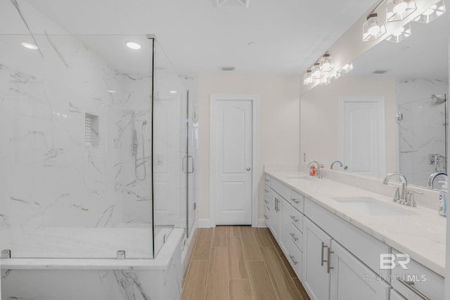 full bathroom featuring a marble finish shower, a sink, and wood finish floors
