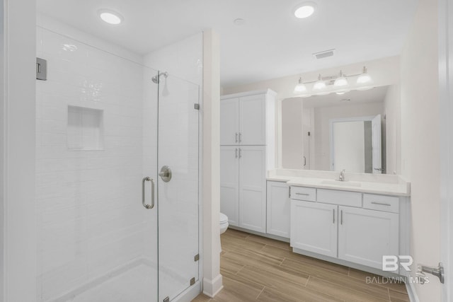 bathroom with visible vents, a shower stall, toilet, wood finish floors, and vanity