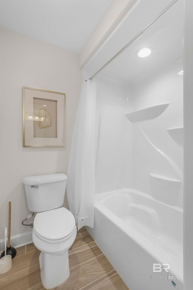 bathroom with baseboards, shower / bathtub combination with curtain, toilet, and wood finished floors