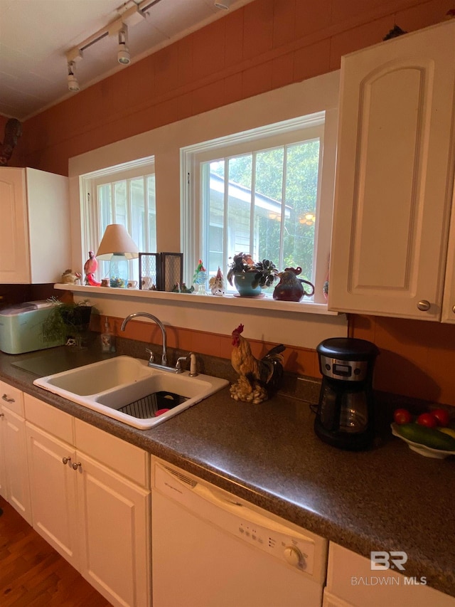 kitchen with sink, rail lighting, white dishwasher, and white cabinetry