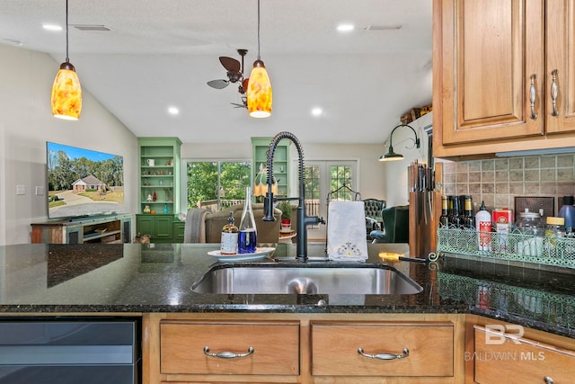 kitchen featuring sink, beverage cooler, dark stone countertops, lofted ceiling, and decorative light fixtures