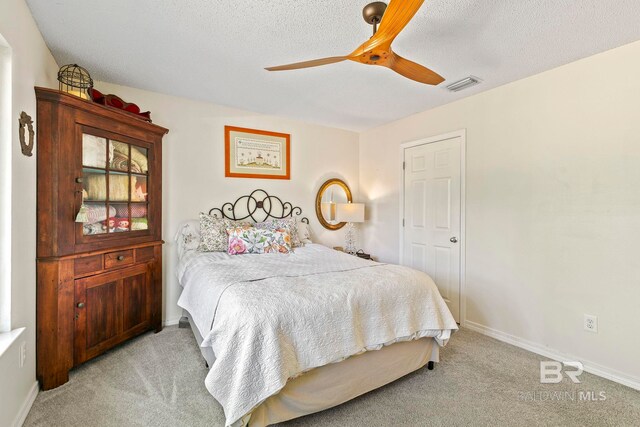 carpeted bedroom with ceiling fan and a textured ceiling