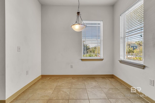 unfurnished dining area with baseboards and light tile patterned floors