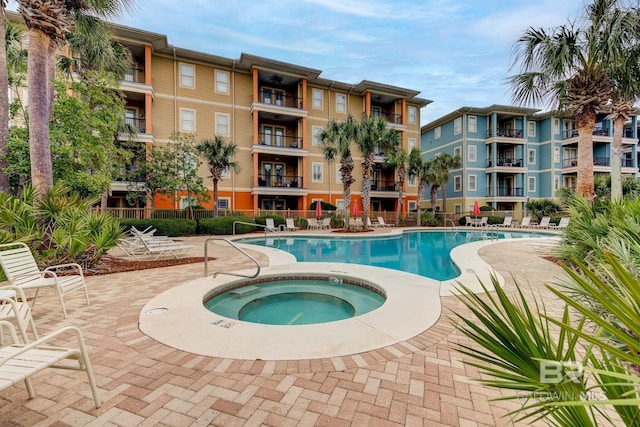 pool featuring a patio area, fence, and a hot tub