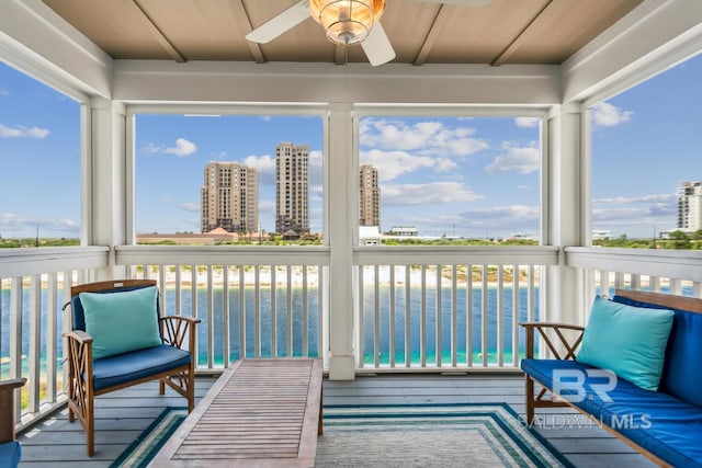 sunroom / solarium with ceiling fan and a water view