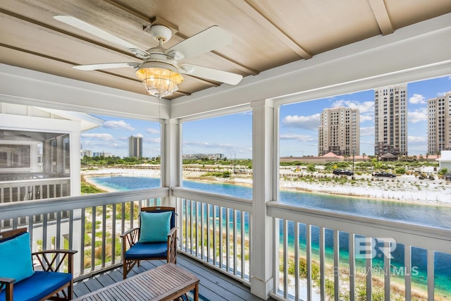 sunroom / solarium with a wealth of natural light, ceiling fan, and a water view