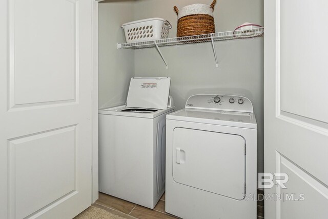 clothes washing area with washing machine and clothes dryer and light tile floors