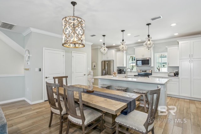 dining area featuring crown molding, sink, and light hardwood / wood-style flooring