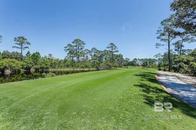 surrounding community with a water view and a lawn