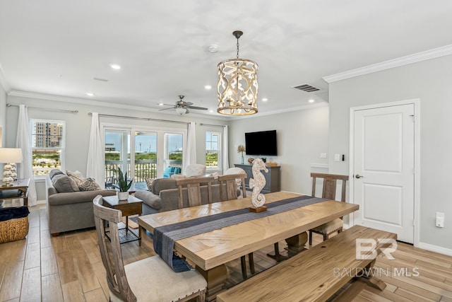 dining space with ceiling fan with notable chandelier, light hardwood / wood-style flooring, and ornamental molding