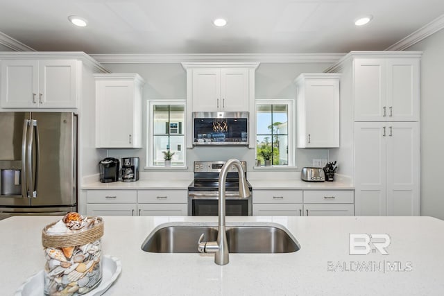 kitchen featuring white cabinetry, appliances with stainless steel finishes, ornamental molding, and light stone counters