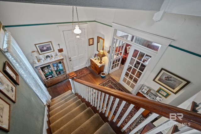 stairs with high vaulted ceiling and wood-type flooring