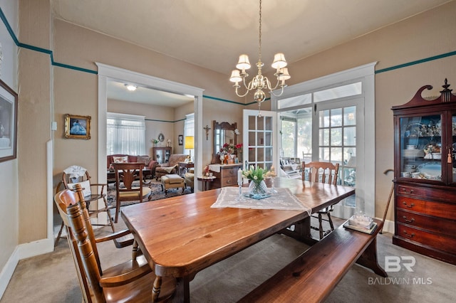 carpeted dining room with an inviting chandelier