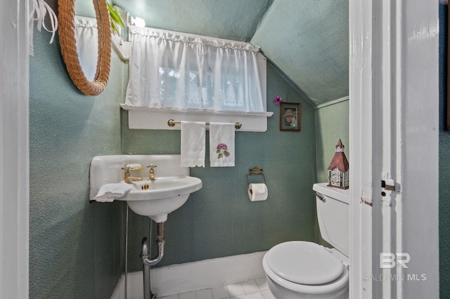 bathroom with lofted ceiling, tile patterned flooring, and toilet