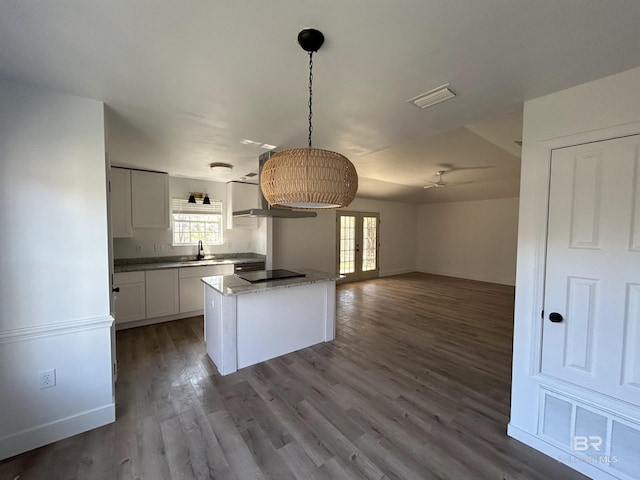 kitchen featuring hanging light fixtures, white cabinetry, a kitchen island, and a healthy amount of sunlight