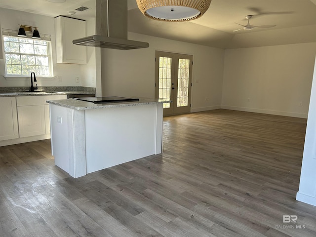 kitchen featuring french doors, sink, island range hood, black electric stovetop, and white cabinets