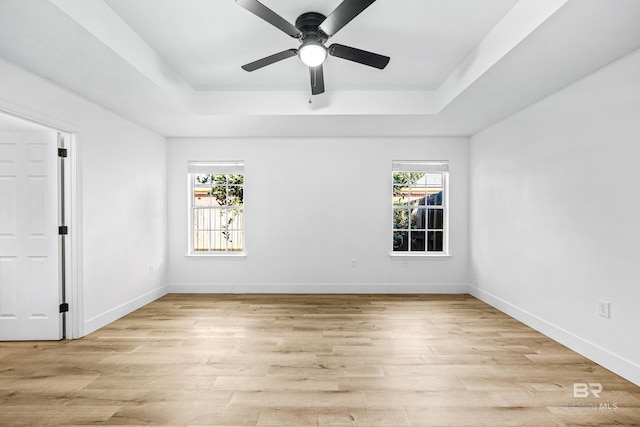 empty room featuring ceiling fan, a raised ceiling, and light hardwood / wood-style flooring