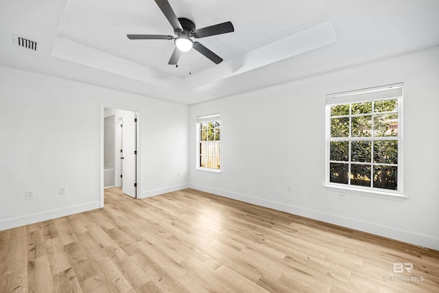 unfurnished room with light hardwood / wood-style floors, a raised ceiling, and ceiling fan