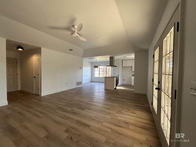 unfurnished living room with dark hardwood / wood-style flooring, vaulted ceiling, and ceiling fan