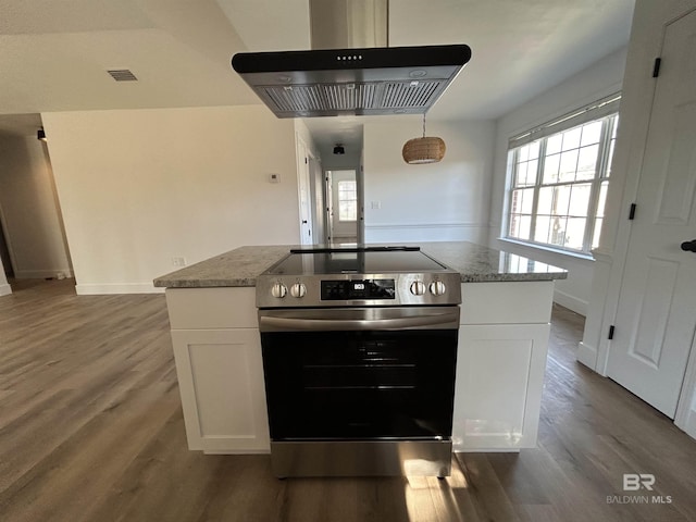 kitchen with island range hood, white cabinets, stainless steel range with electric cooktop, hardwood / wood-style flooring, and light stone countertops