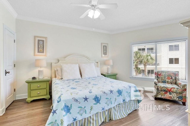 bedroom with baseboards, ornamental molding, ceiling fan, and wood finished floors
