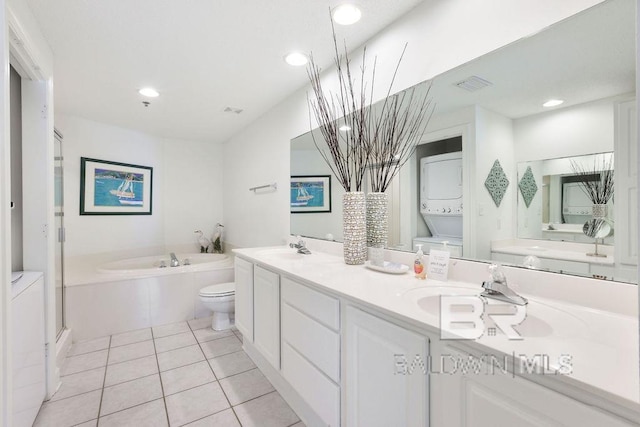 full bath with visible vents, stacked washer and dryer, tile patterned flooring, double vanity, and a bath