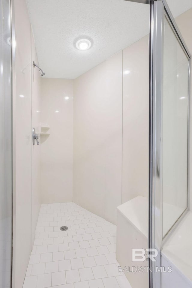 full bath featuring a textured ceiling, a shower stall, and tile patterned flooring