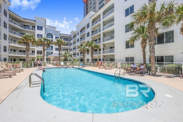 community pool with fence and a patio area