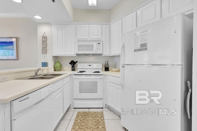 kitchen with a peninsula, light tile patterned flooring, white appliances, white cabinetry, and a sink