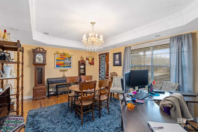 dining area with crown molding, a raised ceiling, dark wood-type flooring, and a chandelier