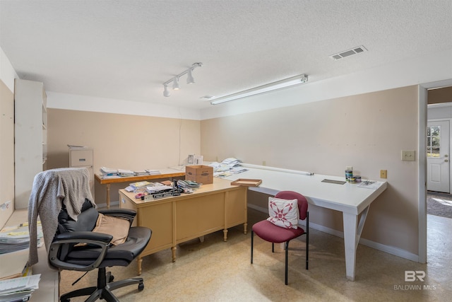 office area with a textured ceiling and rail lighting