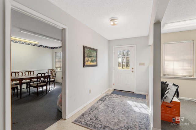 foyer featuring a textured ceiling and light colored carpet